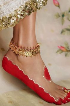 a woman's feet wearing red shoes and gold jewelry