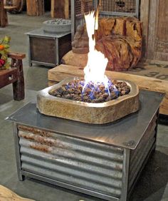 a fire pit sitting on top of a metal table in a room filled with furniture