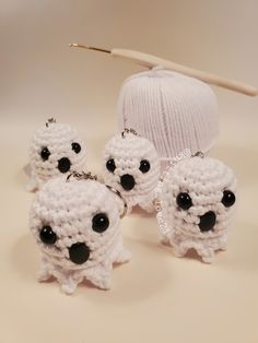 three small white crocheted sheep with black eyes are next to a ball of yarn