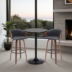 two chairs and a table in front of a fire place with a window overlooking the ocean