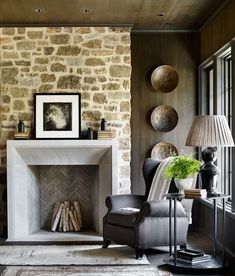 a living room filled with furniture and a fire place in front of a stone wall