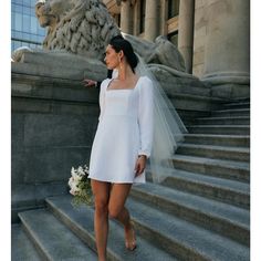 a woman in a white dress is standing on some steps