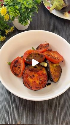 a white bowl filled with sliced up vegetables on top of a wooden table next to a potted plant