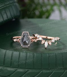 two rings with diamonds on them sitting on top of a green surface