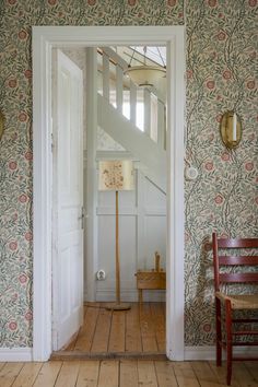 an open door leading into a room with floral wallpaper on the walls and wooden floors