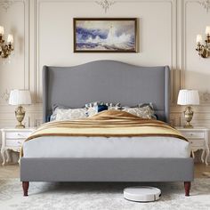 a bed with a gray headboard and foot board in a white room next to two lamps