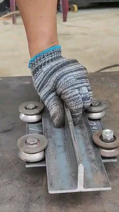 a person wearing gloves and holding onto a skateboard with wheels on the ground in front of them