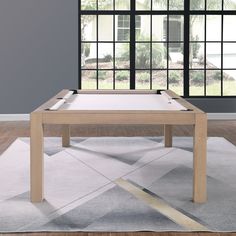 a pool table sitting on top of a rug in front of a window with black panes