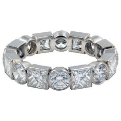 a white gold ring with five stones on the side and four rows of diamonds around it