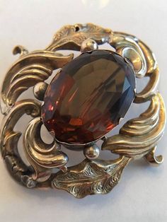 "This is a Very Special Piece. Probably the oldest piece in my inventory. This is an Antique Georgian Brooch with a Large Amber/Brown Topaz in the Center. It is possible it is a Paste Stone. It also has an open hook in the back, at the top, so it can be worn as a pendant if desired. This piece is really well made and in very good condition considering its age. The piece is tested to be 9K Yellow Gold. The large stone is about 1 3/4 \" x 1 3/4\" tall. It weighs 10.7 grams without the stone. I am Heirloom Oval Brooch For Formal Occasions, Elegant Baroque Brooches For Formal Occasions, Ornate Yellow Gold Brooch For Formal Occasions, Antique Oval Brooches For Evening, Ornate Brooches With Intricate Design For Formal Occasions, Vintage Gemstone Brooches For Formal Occasions, Ornate Baroque Brooches For Formal Occasions, Formal Oval Hallmarked Brooches, Ornate Oval Brooches For Formal Occasions