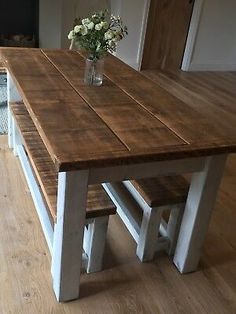 a wooden table with two benches next to it on a hard wood floor in a living room