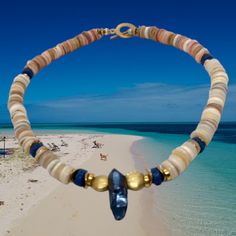 Experience the tropical vibes with our stunning 17" Fiji Choker Necklace of Lapis Lazuli, Gold, and beach-colored shells and beads. From the glint of gold to the mesmerizing blue of the Lapis Lazuli, this exquisite piece will make you feel like you've escaped to an island paradise! Toggle style closure. Unisexy! Beach Necklaces, Beach Color, Island Paradise, Island Beach, Tropical Vibes, Lapis Lazuli, Bracelets For Men, Make You Feel, Necklaces Bracelets