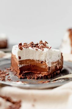 a piece of cake on a plate with chocolate shavings and whipped cream topping