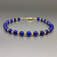 "Bracelet with polished Lapis Lazuli and gold plated beads and clasp. Unique gift for her or him, wife, friend, mother September and December birthstone, 9 year anniversary.  The dark pure natural Lapis Lazuli beads, with enclosures of pyrite and calcite, are set 1 to 1 with tiny 14K gold plated beads. The stones are strung on stainless steel and finished with a secure clasp.  All our jewelry is handmade and natural stone, slight differences and color and size may occur. All our gold plated items are Sterling silver and three times 14K gold plated. Stone size: 5 mm metal pieces: 3 mm carats: 25 Lapis Lazuli: Throughout the ages it was a symbol of royalty. The Egyptians, Sumerians and Babylonians believed it is associated with the divine feminine. Catherina the Great was a great admirer of Gold Beaded Lapis Lazuli Bracelets, Spiritual Gold Bracelet With Round Beads, Elegant Beaded Bracelets With Natural Stones For Gift, Elegant Yellow Gold Beaded Bracelets With Gemstones, Hand-strung Gold Lapis Lazuli Bracelets, Gold Lapis Lazuli Spiritual Bracelets, Elegant Blue Rondelle Bracelets, Elegant Hand-strung Jewelry Gift, Gold Lapis Lazuli Beaded Bracelets With Round Beads