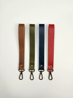 three different colored leather lanyards hanging from hooks