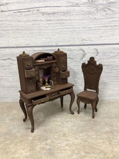 an antique desk and chair are shown in front of a wooden wall