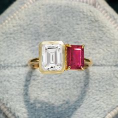 an emerald and pink tourmaline ring sitting on top of a white cloth bag