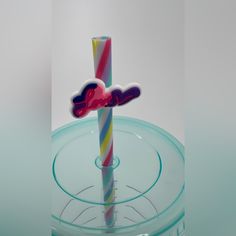 a colorful candle with the word love on it in front of a clear glass holder