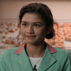 a woman wearing a green coat standing in front of doughnuts on the wall