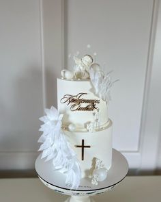 a white wedding cake with flowers and a cross on top