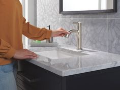 a person standing in front of a sink with a faucet on the side