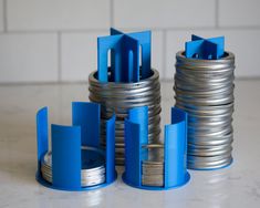 several stacks of silver and blue metal objects on a white counter top with tile in the background