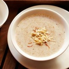 a white bowl filled with soup on top of a wooden table next to two plates