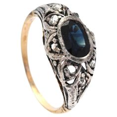 Late XIX - early XX century. European Ring with Silver on 18K Gold openwork crown with natural Blue Sapphire and 8 rose cut Diamonds. Not hallmarked, band tested solid 18K . Medium Blue natural Sapphire, old oval cut with inclusions and internal flaws, measuring ca. 7.5 mm x 5.5 mm x 3.2 mm deep / ca. 1.25 ct . Eight Diamonds rose cut circa ca. 0.5 ctw / total. All stones have backs open. Used fine condition. Natural aged patina on metals. Size: Ø 7.5 US / Ø 17.75 mm. The floret/ crown measures Antique Sapphire Ring With 17 Jewels, Antique Yellow Gold Sapphire Ring With Rose Cut Diamonds, Antique Sapphire Diamond Ring With Rose Cut, Antique Oval Sapphire Ring With Rose Cut Diamonds, Vintage Sapphire Rings With Intricate Design, Victorian Yellow Gold Sapphire Ring, Ornate Yellow Gold Filigree Ring With Gemstone, Heirloom Oval Sapphire Ring With Intricate Design, Antique 14k Gold Filigree Ring With Rose Cut Diamonds