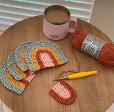 crocheted coasters and yarn on a table next to a cup of coffee