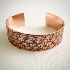 "This bracelet is formed from 16 gauge (1.3mm) pure copper that measures 3/4\" wide. It is 6\" long with a gap of a little over 1\" and will fit most women's wrists. It can be gently adjusted by bending slightly to make it easy to put on and take off and comfortable to wear. The bracelet is hand stamped with an Art Deco fan motif and sealed to protect from tarnish. If you think you may need a different size just leave a note at checkout and I'll contact you about sizing. The bracelet will arrive Adjustable Etched Bronze Cuff Bracelet, Adjustable Etched Bronze Bracelets, Adjustable Bronze Etched Cuff Bracelet, Engraved Rose Gold Cuff Bangle Bracelet, Engraved Rose Gold Bangle Cuff Bracelet, Engraved Rose Gold Cuff Bangle, Bronze Cuff Bracelet Gift, Bronze Copper Cuff Bracelet As Gift, Handmade Rose Gold Copper Cuff Bracelet