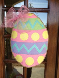 an easter egg door hanger is hanging on the front door with a pink bow