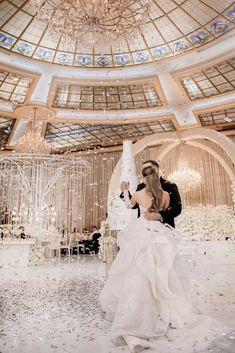 a bride and groom standing in front of a chandelier