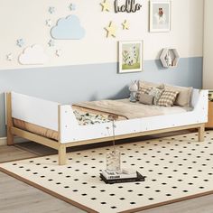 a white bed sitting on top of a wooden floor next to a wall filled with pictures