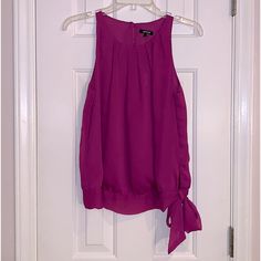 Sleeveless Blouse With Pleading Around Neckline Has Band At The Bottom And Ties In A Bow. The Back Is Keyhole With A Button Closure, Size Small, New With Tags Has An Extra Button Purple Casual Tank Top For Party, Casual Purple Tank Top For Party, Purple Sleeveless Tank Top For Party, Chic Purple Tank Top For Spring, Elegant Purple Tank Top, Purple Sleeveless Vest Top, Purple Sleeveless Blouse For Spring, Purple Casual Halter Neck Top, Purple Tank Top For Parties