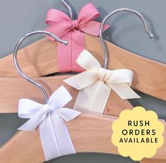 three wooden hangers with white and pink bows on them, one has a large bow