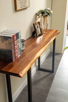 a wooden table topped with books and a vase filled with flowers on top of it