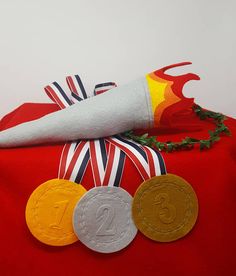 a red bag with three different colored medals on it's side and a white object in the background