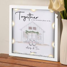 a white vase with flowers in it next to a photo frame that says together we are favorite place to be