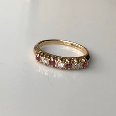 A Vintage 9 carat gold Ruby and diamond ring. This beautiful piece holds all seven stones neatly in line, with a diamond in between each glowing ruby. The settings hold each stone neatly while displaying all the sparkle from them. CONDITION: Wear consistent with age and use. Please see photos for more detail. ASSAYED IN BIRMINGHAM CIRCA 1989 SETTING (ACROSS): 21mm SETTING WIDTH: 3.5mm RUBY DIAMETER: 2mm DIAMOND DIAMETER: 2mm BAND WIDTH (SMALLEST): 2mm RING SIZE: UK: N | US: 6 1/2 WEIGHT: 2.4 grams (UZZ) Ruby Ring Designs, Diamond Rings With Price, Half Eternity Ring Diamond, Ruby And Diamond Ring, Rose Gold Diamond Ring, Half Eternity Ring, Garnet Rings, Multi Stone Ring, Ruby Ring