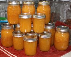 there are many jars with food in them on the table and one is filled with orange liquid