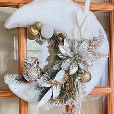 a wreath with an owl and christmas decorations hanging on the side of a wooden door