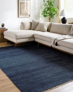 a living room with a large blue rug on the floor and a white sectional couch