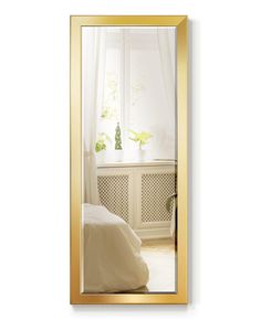 a mirror that is on the wall above a bed in a room with white walls