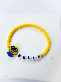 a yellow beaded bracelet with the word hello written on it and a minion charm