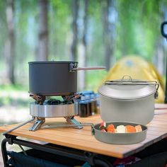 an outdoor stove with pots and pans sitting on top of it next to a picnic table