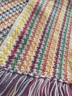 a multicolored crocheted blanket laying on top of a bed