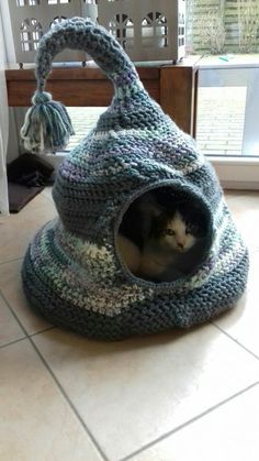 a cat in a knitted bag on the floor