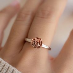 a woman's hand with a rose ring on it