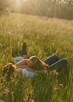 two women are laying in the grass together