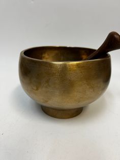 a brass bowl with a wooden spoon in it